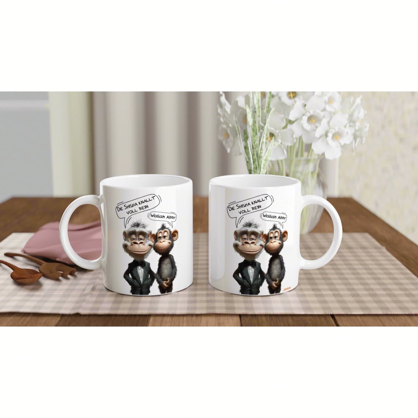 Two white mugs with cartoon monkeys in suits and speech bubbles, on a striped placemat with a vase of white flowers.