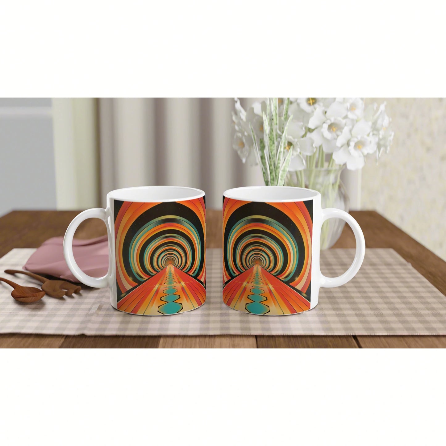Two white mugs featuring a colorful psychedelic tunnel design on a checkered placemat, with flowers in the background.