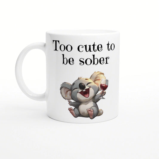 White ceramic mug featuring a joyful cartoon koala holding a wine glass with the slogan Too cute to be sober.