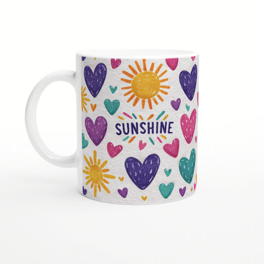 White ceramic mug with playful doodle artwork: multicolored hearts and suns surrounding the word SUNSHINE.