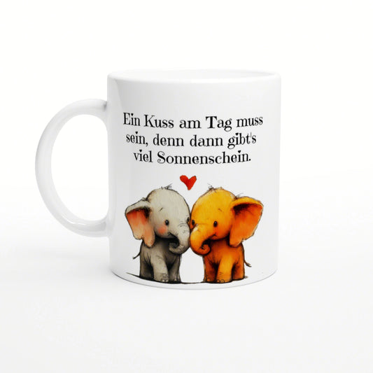White mug with two cartoon elephants kissing, a small red heart, and a German caption about sunshine.