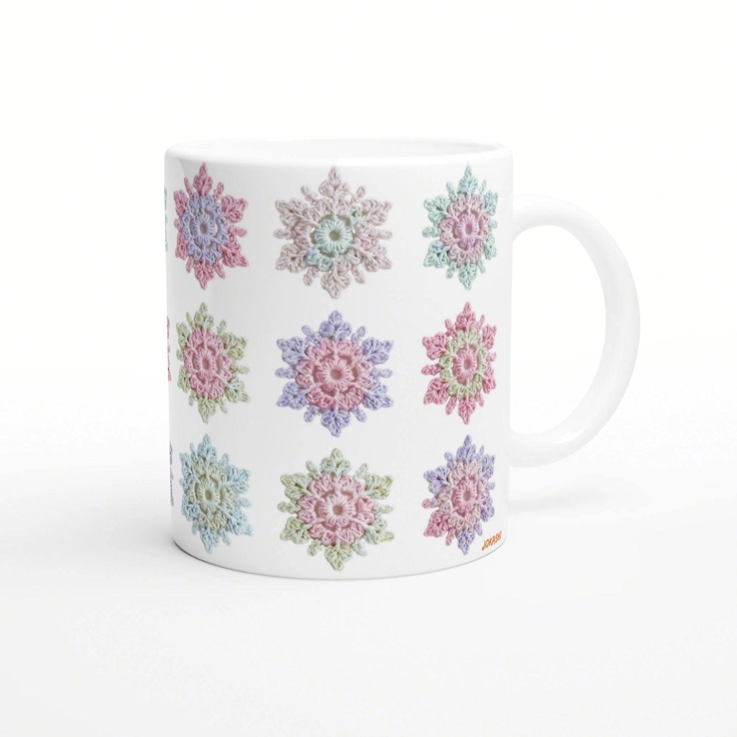 White ceramic mug featuring pastel crochet-style flower motifs around its surface; product mockup.