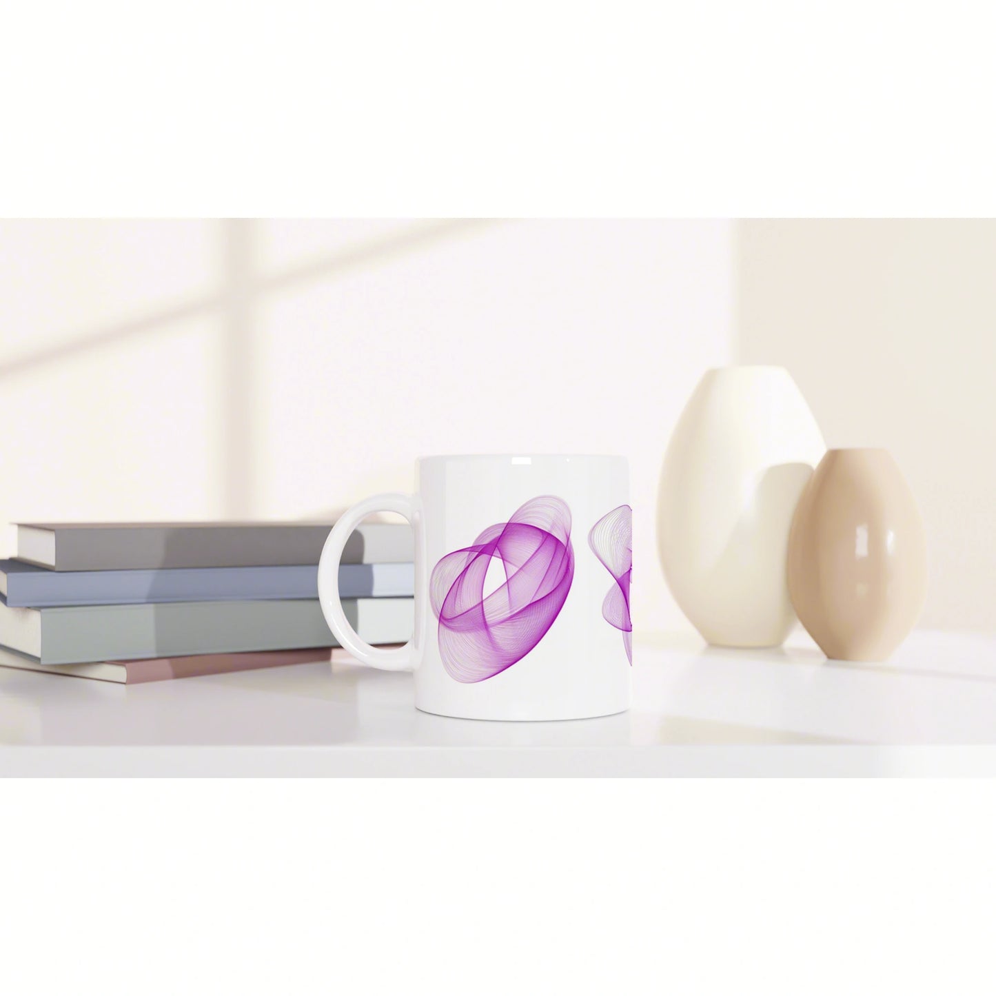 White mug with a purple abstract swirl pattern on a clean desk beside stacked books and cream-beige ceramic vases.