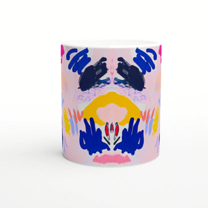 Abstract symmetrical painting on a white ceramic mug; pink backdrop with navy blue shapes, yellow arc, and pink/red accents.