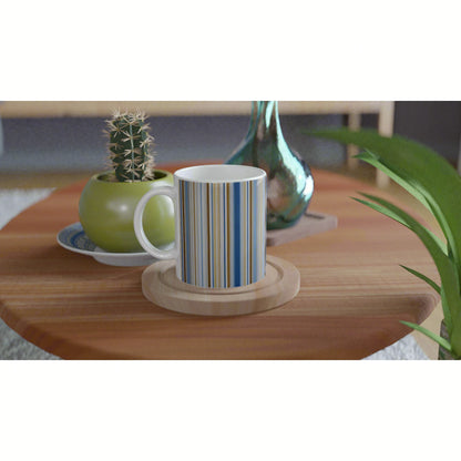 Blue and white striped mug on a wooden coaster atop a wooden table with a potted cactus and turquoise vase nearby.