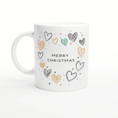 Product mockup: white ceramic mug with Merry Christmas text surrounded by hand-drawn multicolored hearts and tiny stars.