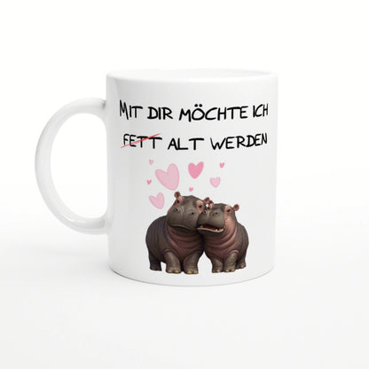 White ceramic mug with black German text Mit dir moechte ich fett alt werden, and two hippos with pink hearts.