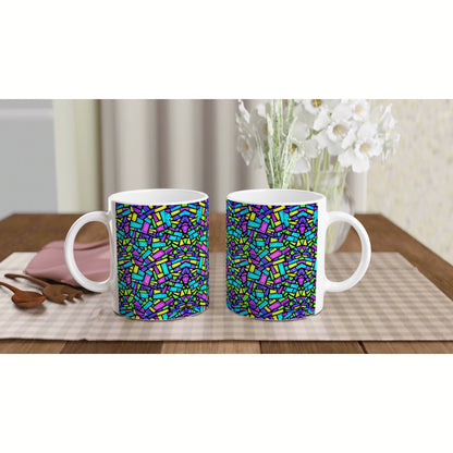 Mockup: two white ceramic mugs with a multicolor mosaic pattern on a wooden table, checkered placemat, and white flowers.