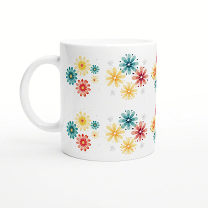 Product mockup: white ceramic mug adorned with scattered colorful flowers in yellow, teal, orange and red on a white background.