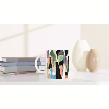 Mug with an abstract colorful pattern on a white desk, beside stacked books and pastel vases (product mockup).