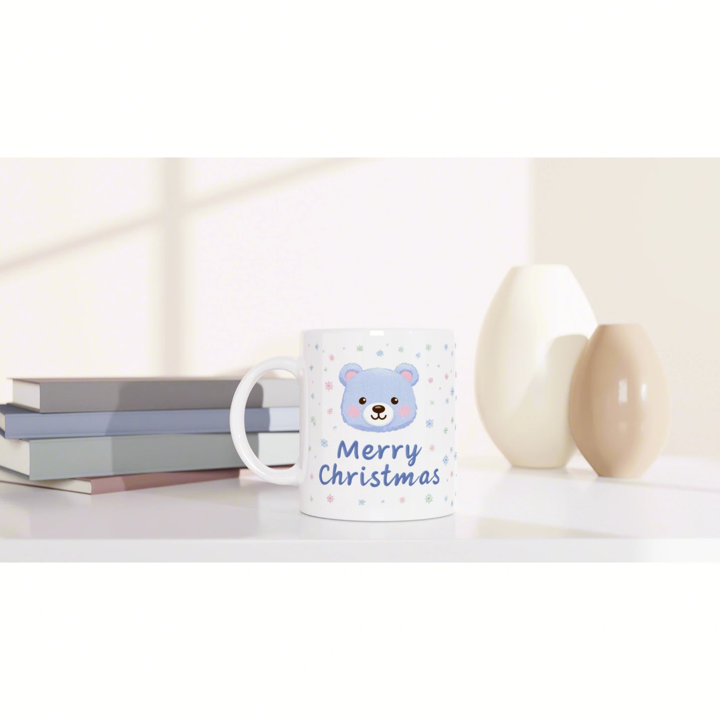 Mug with a blue bear, 'Merry Christmas' text, and snowflakes; pastel books and decorative vases in the background.