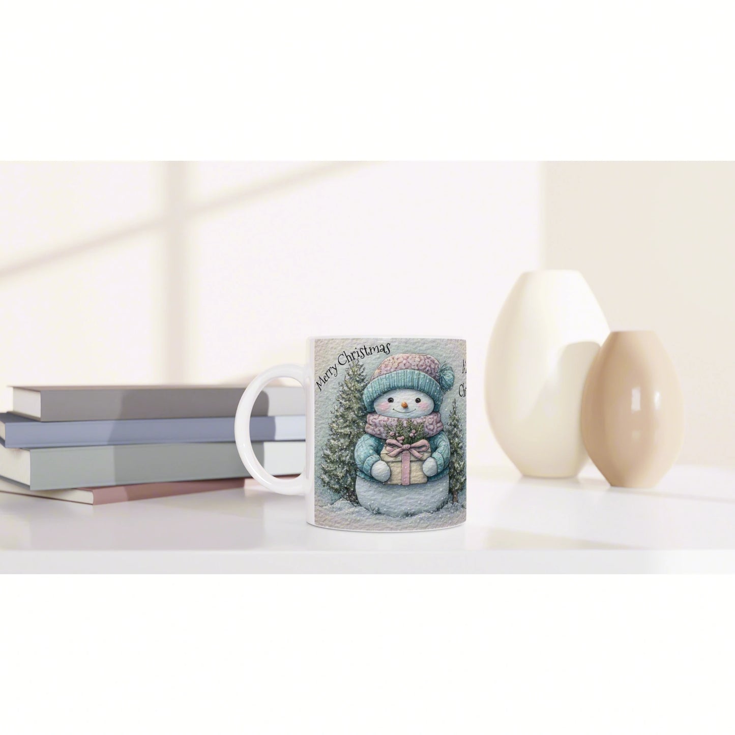 Mug with a Christmas snowman illustration, trees and a gift, resting on a shelf beside books and decorative ceramic vases.