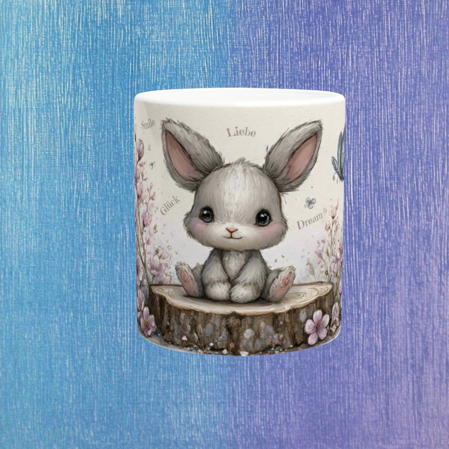 White ceramic mug featuring a cute gray bunny sitting on a tree stump, surrounded by pastel flowers; product mockup.