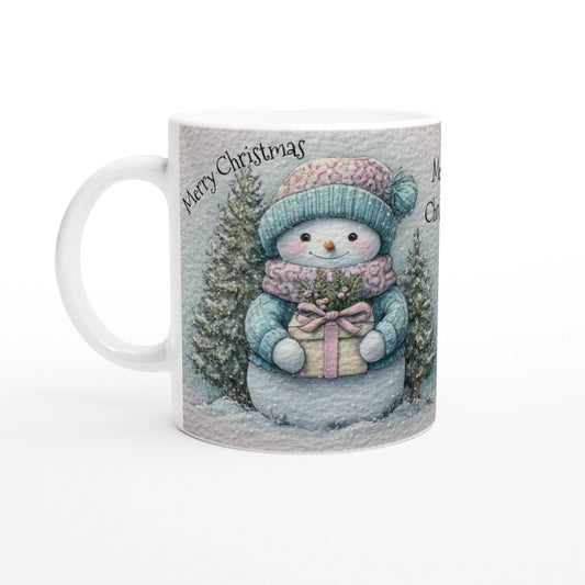 Mug with a cute snowman in teal hat and scarf holding a gift among snowy trees; Merry Christmas