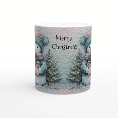 Mug mockup with 'Merry Christmas' text featuring a snowy winter scene: snowmen in teal hats, pine trees, and wrapped gifts.