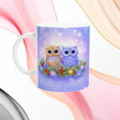 Mug mockup with two cute owls perched on a festive pine wreath, pinecones and ornaments, against a purple snowy background.