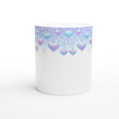 Product mockup: white ceramic mug with pastel gradient top featuring hanging blue and pink heart ornaments and snowflakes.