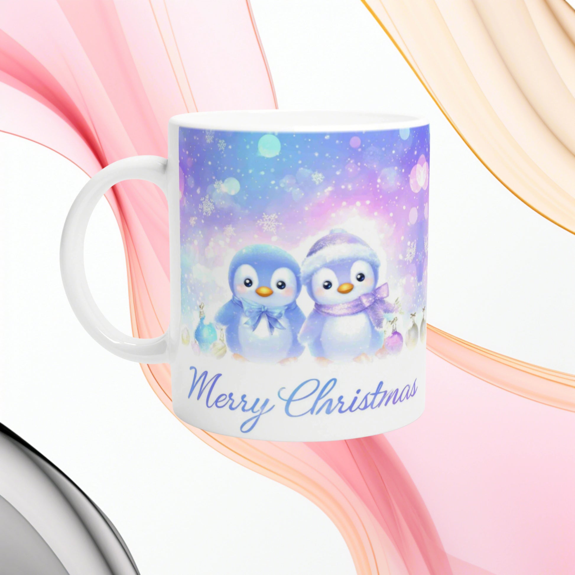 White mug featuring a pastel Christmas scene with two cute penguins in blue and lavender and the Merry Christmas text.