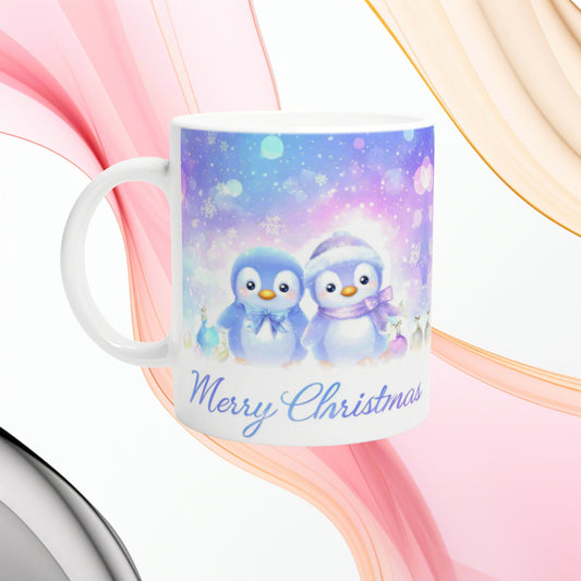 White mug featuring a pastel Christmas scene with two cute penguins in blue and lavender and the Merry Christmas text.