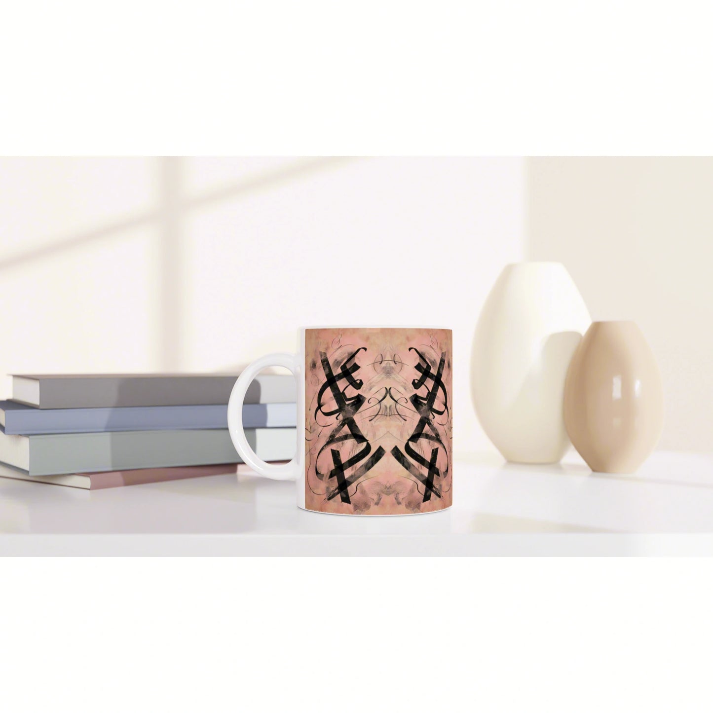 Mug mockup with pink background and a black mirrored abstract pattern, set on a white shelf with books and ceramic vases.