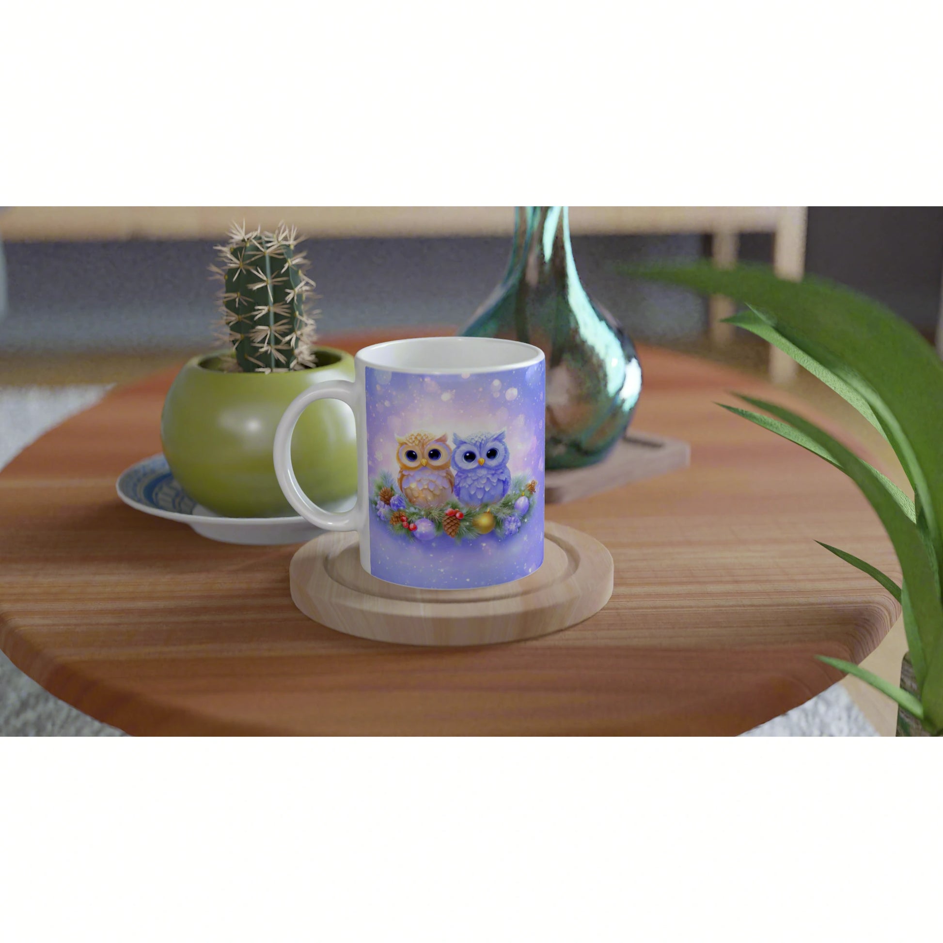 Product mockup: mug showing two owls in a snowy winter scene on a wooden table, with a cactus pot and a glass vase nearby.