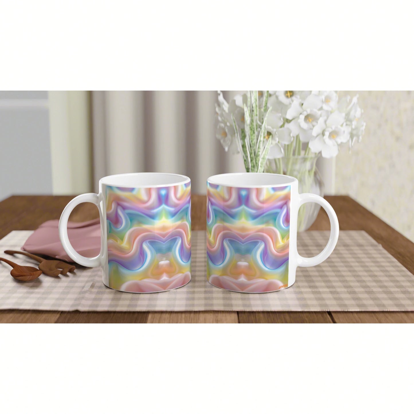 Pair of white ceramic mugs with rainbow swirl patterns on a beige checkered placemat atop a wooden table.
