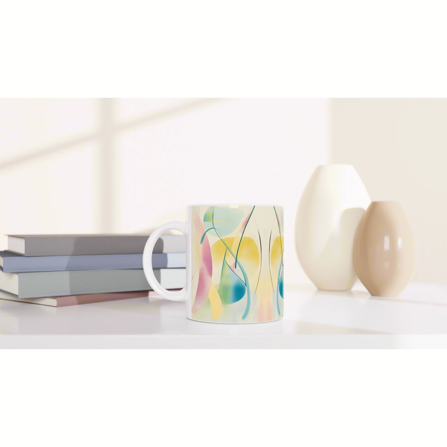 Product mockup: colorful abstract mug on a white shelf with pastel vases and a stack of books in the background.