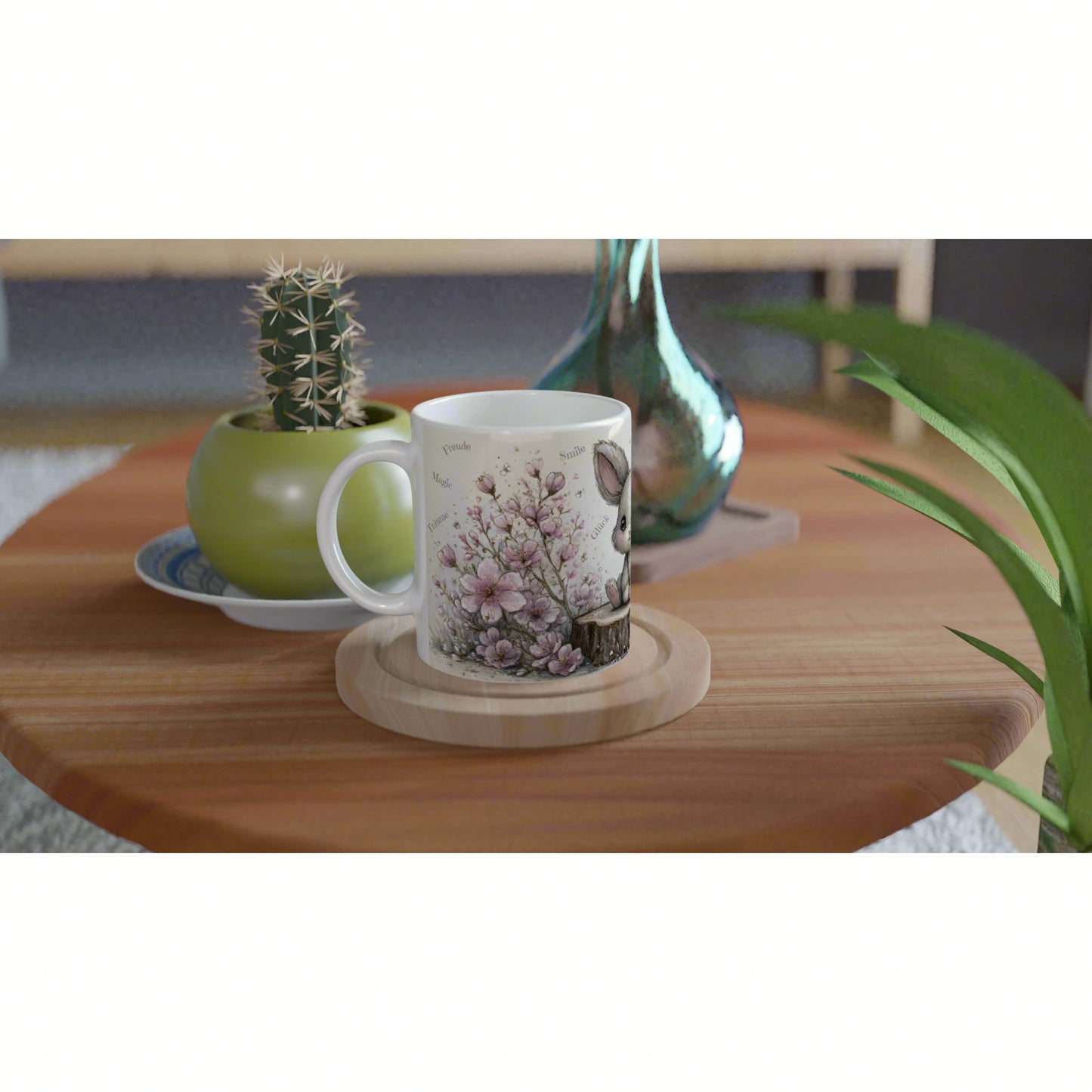 Product mockup: white mug with pink floral illustration on a wooden table, beside a green plant pot and teal vase.