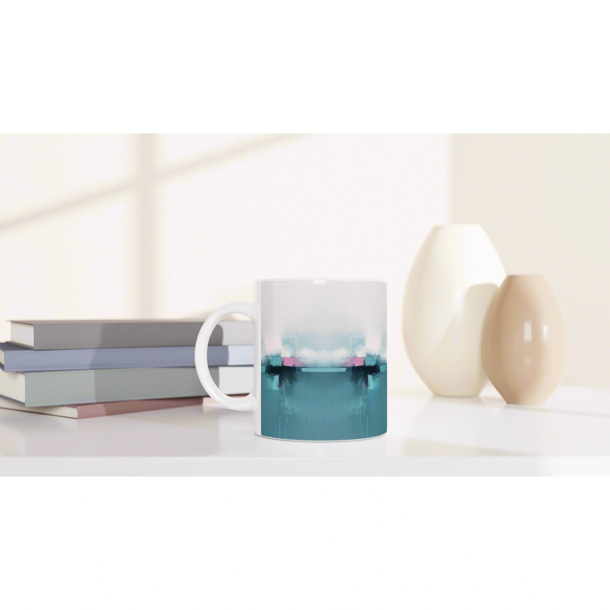 Product mockup: white mug with teal-blue abstract gradient, displayed on a shelf with stacked books and cream vases.