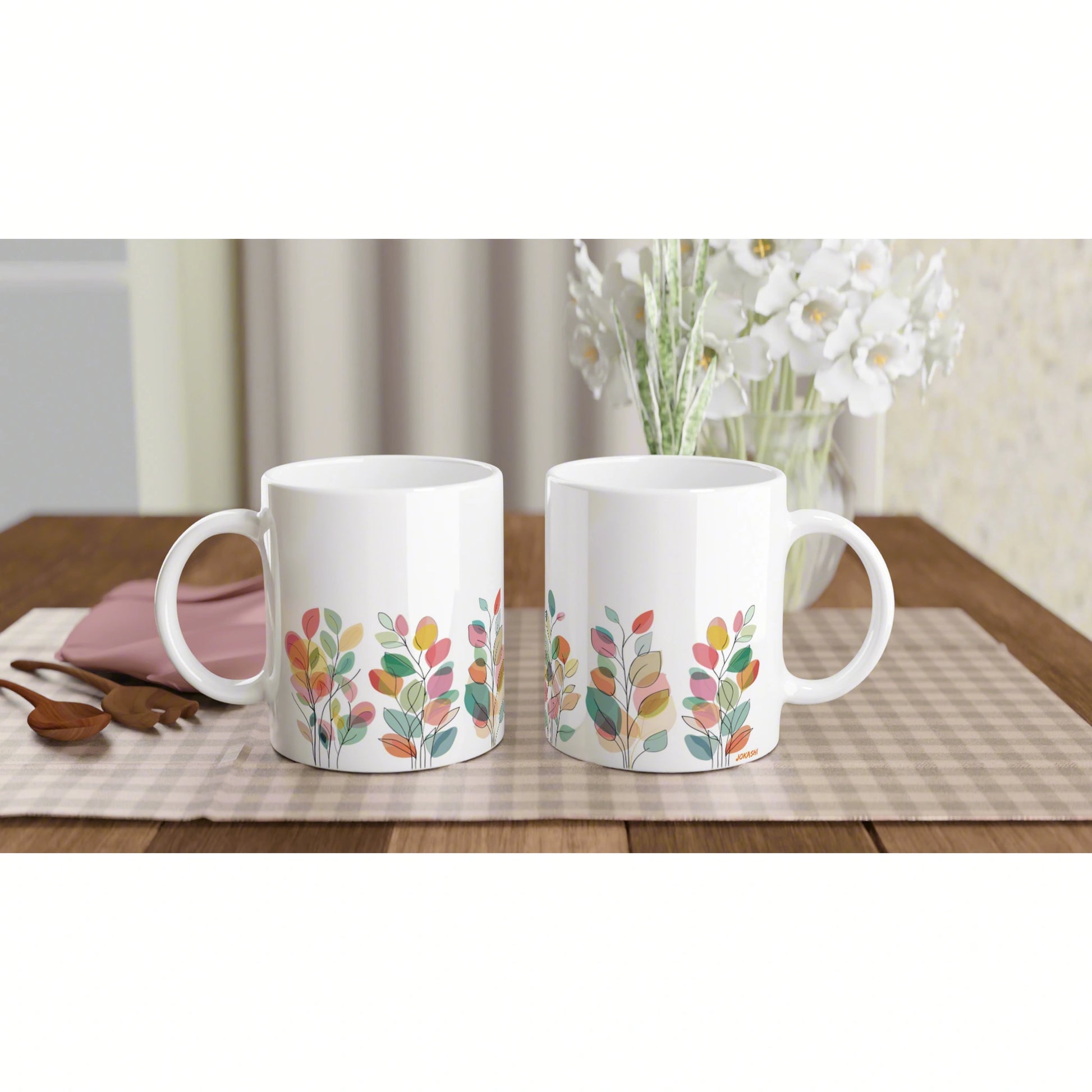 Product mockup: two white ceramic mugs with colorful leafy pattern placed side by side on a wooden table.