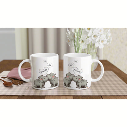 Product mockup: two white mugs featuring cartoon hippos kissing with hearts on a wooden table.