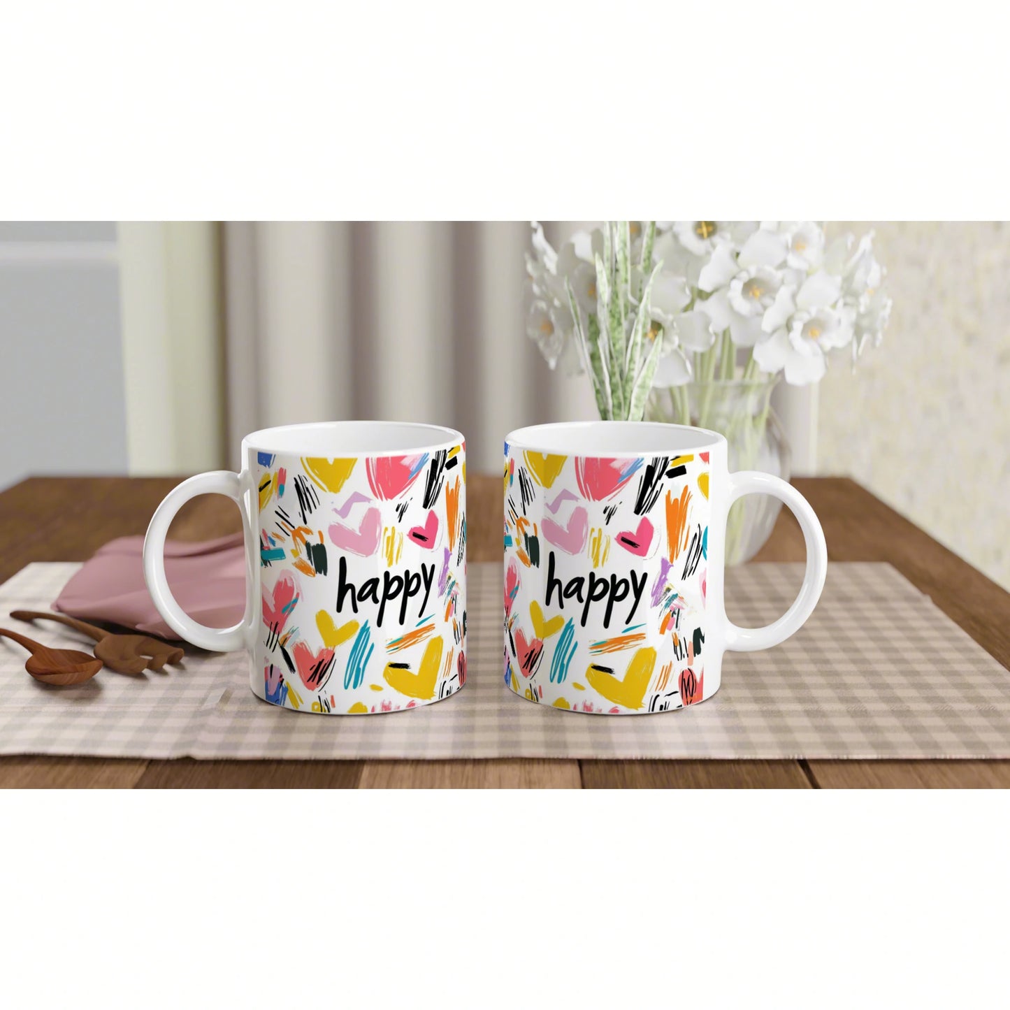 Product mockup: two white mugs with colorful abstract brushstrokes and the word 'happy' on a wooden table.