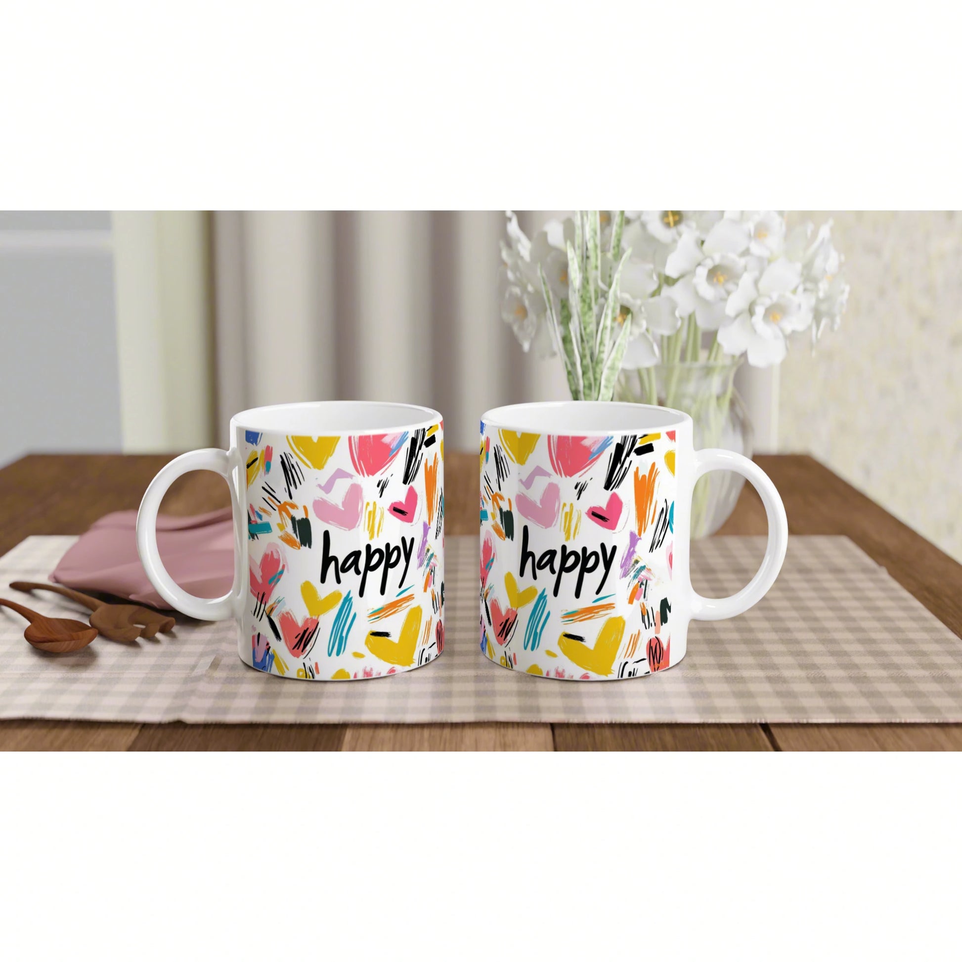 Product mockup: two white mugs with colorful abstract brushstrokes and the word 'happy' on a wooden table.