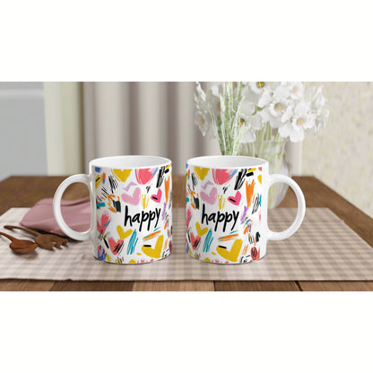 Product mockup: two white mugs with colorful abstract brushstrokes and the word 'happy' on a wooden table.