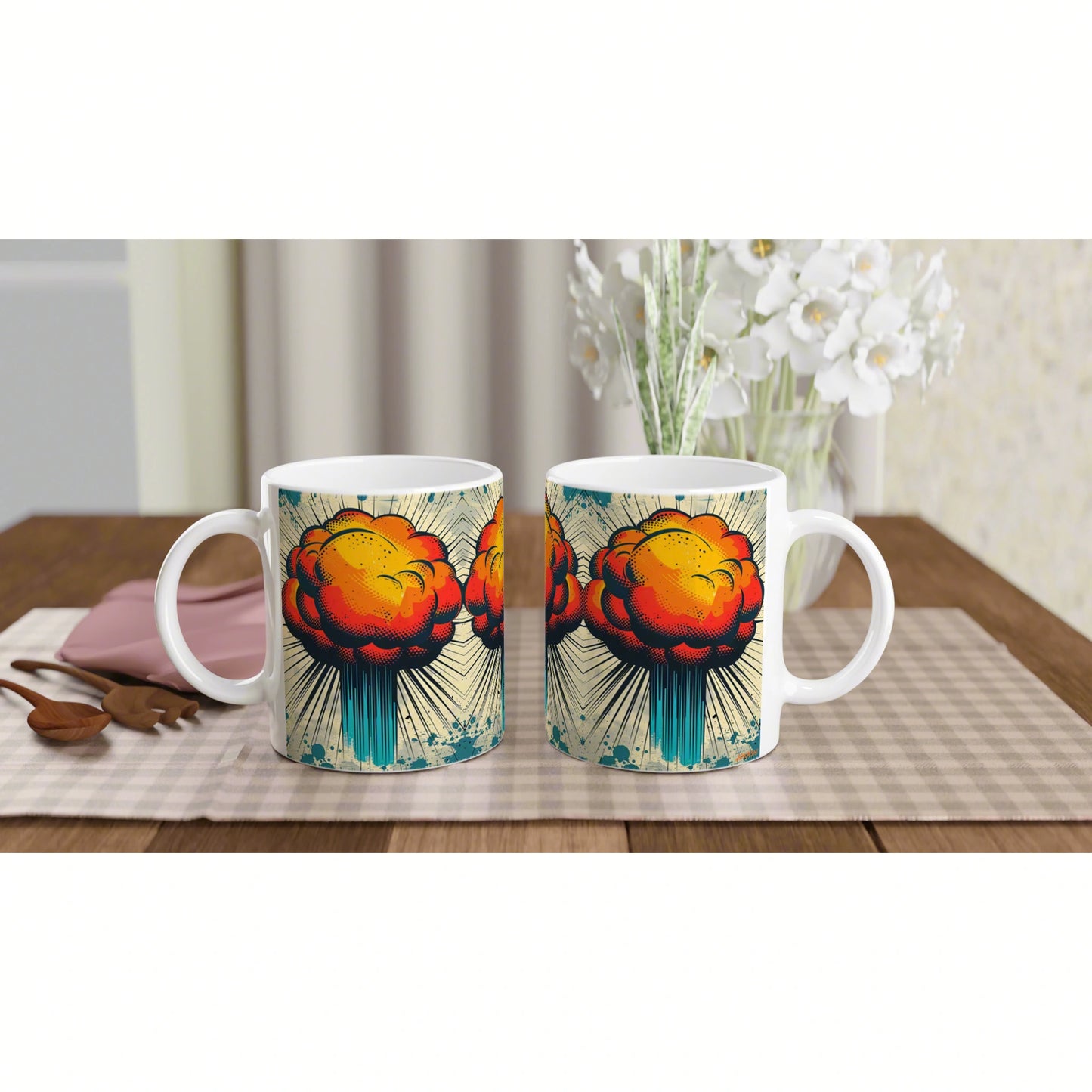 Product mockup: two white mugs with a bright pop-art explosion graphic on a checkered placemat.