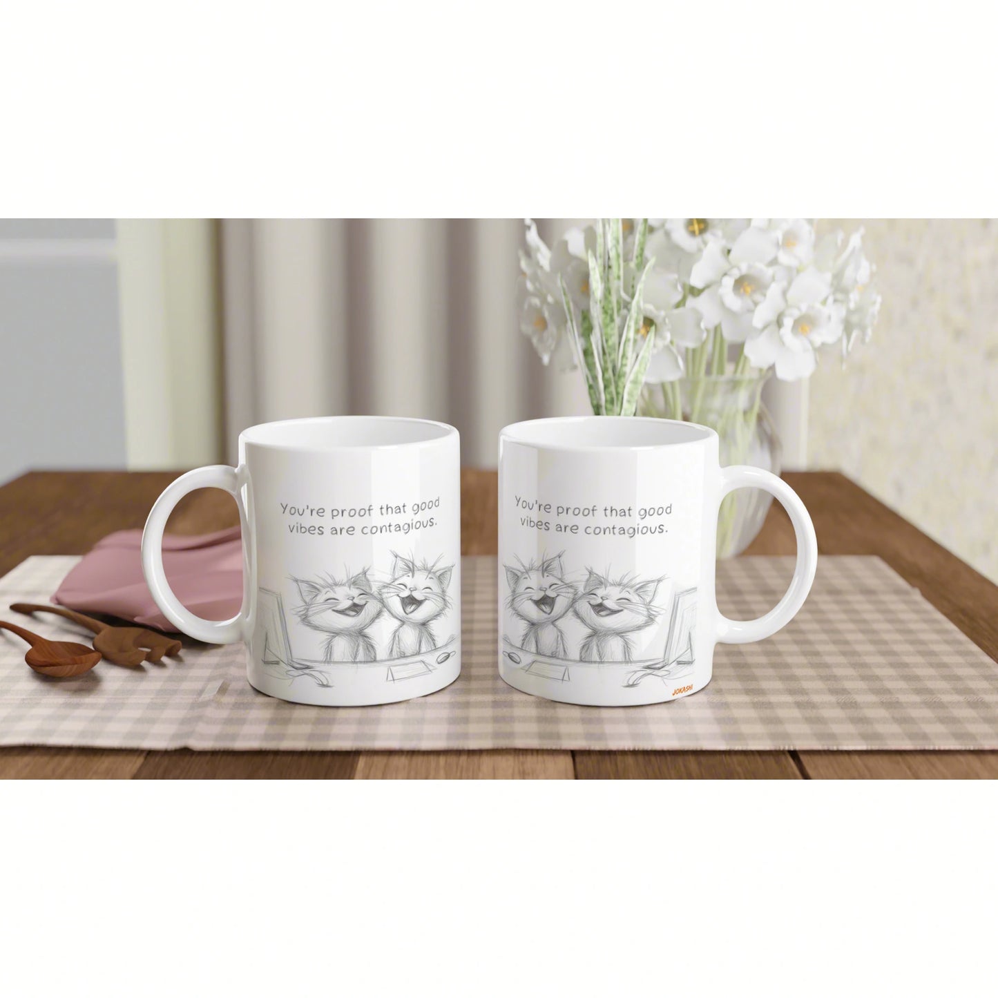 Product mockup: two white mugs with cat sketch and the quote 'You're proof that good vibes are contagious' on a wooden table.