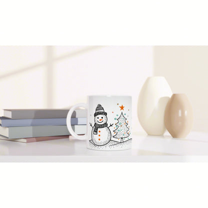 Product mockup: white ceramic mug with snowman and Christmas tree illustration, shown on a shelf with books and vases.