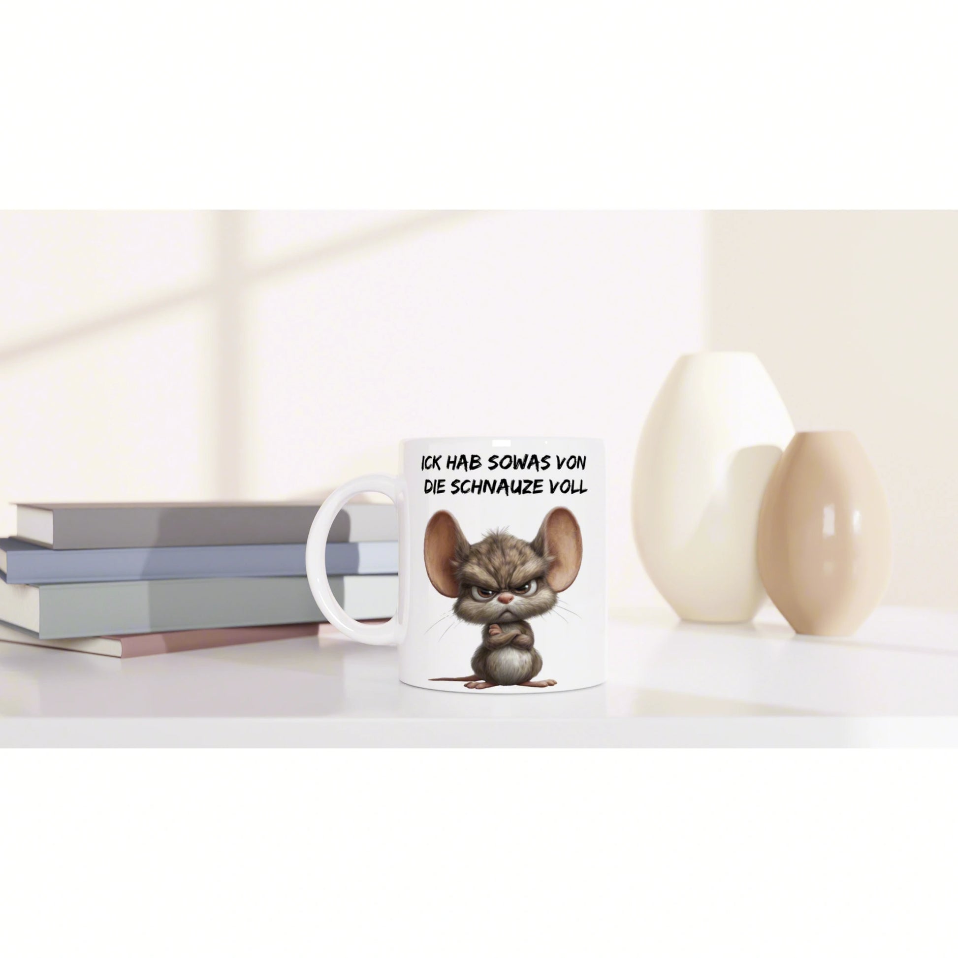 Product mockup: white mug with an angry cartoon mouse and German slogan, on a shelf with books and decorative vases.