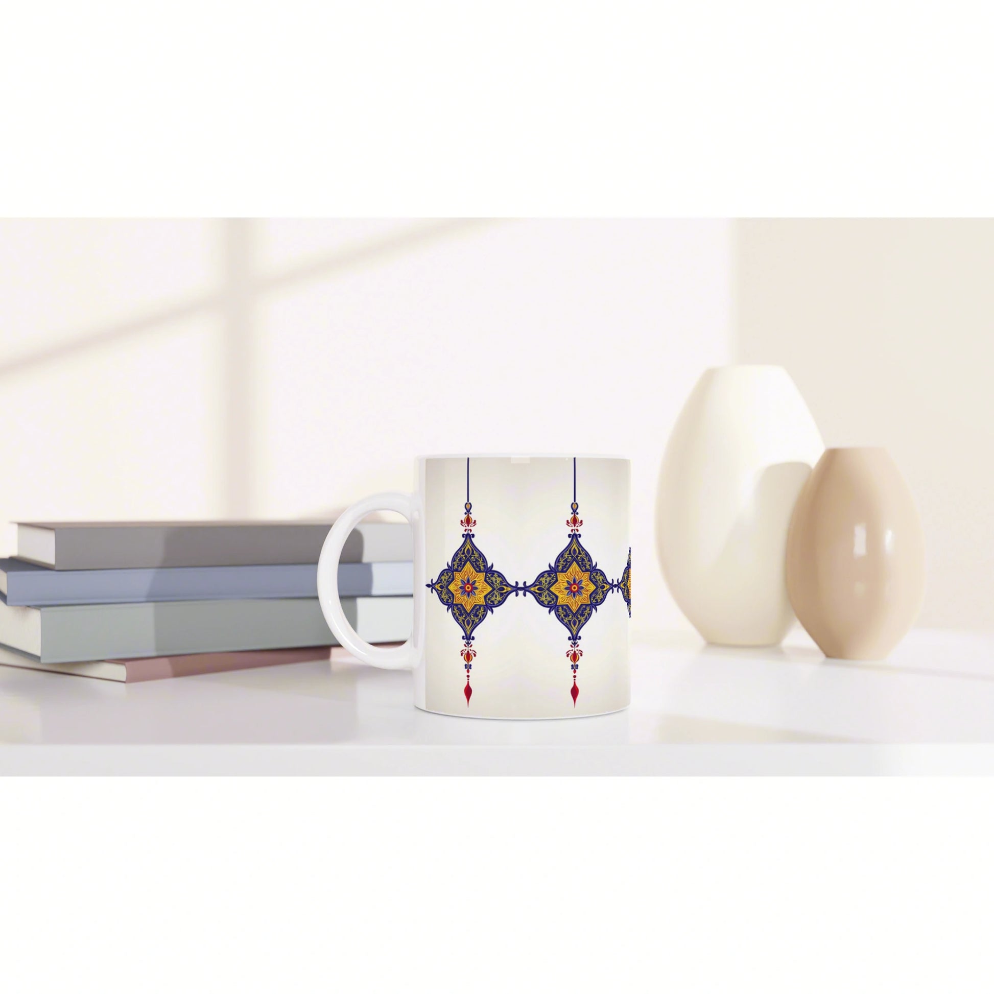 Product mockup: white mug with blue and gold ornamental pattern, placed on a shelf with books and ceramic vases.