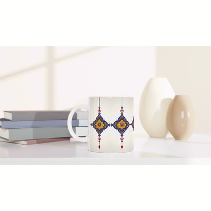 Product mockup: white mug with blue and gold ornamental pattern, placed on a shelf with books and ceramic vases.