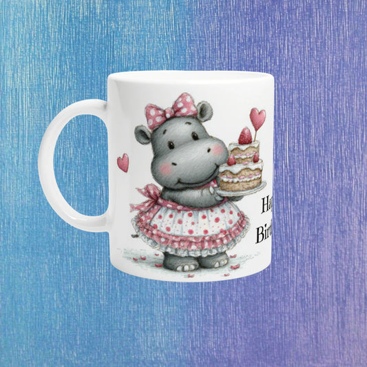 Product mockup: white mug with a cute illustrated hippo in a pink polka-dot dress, holding a strawberry cake with hearts.