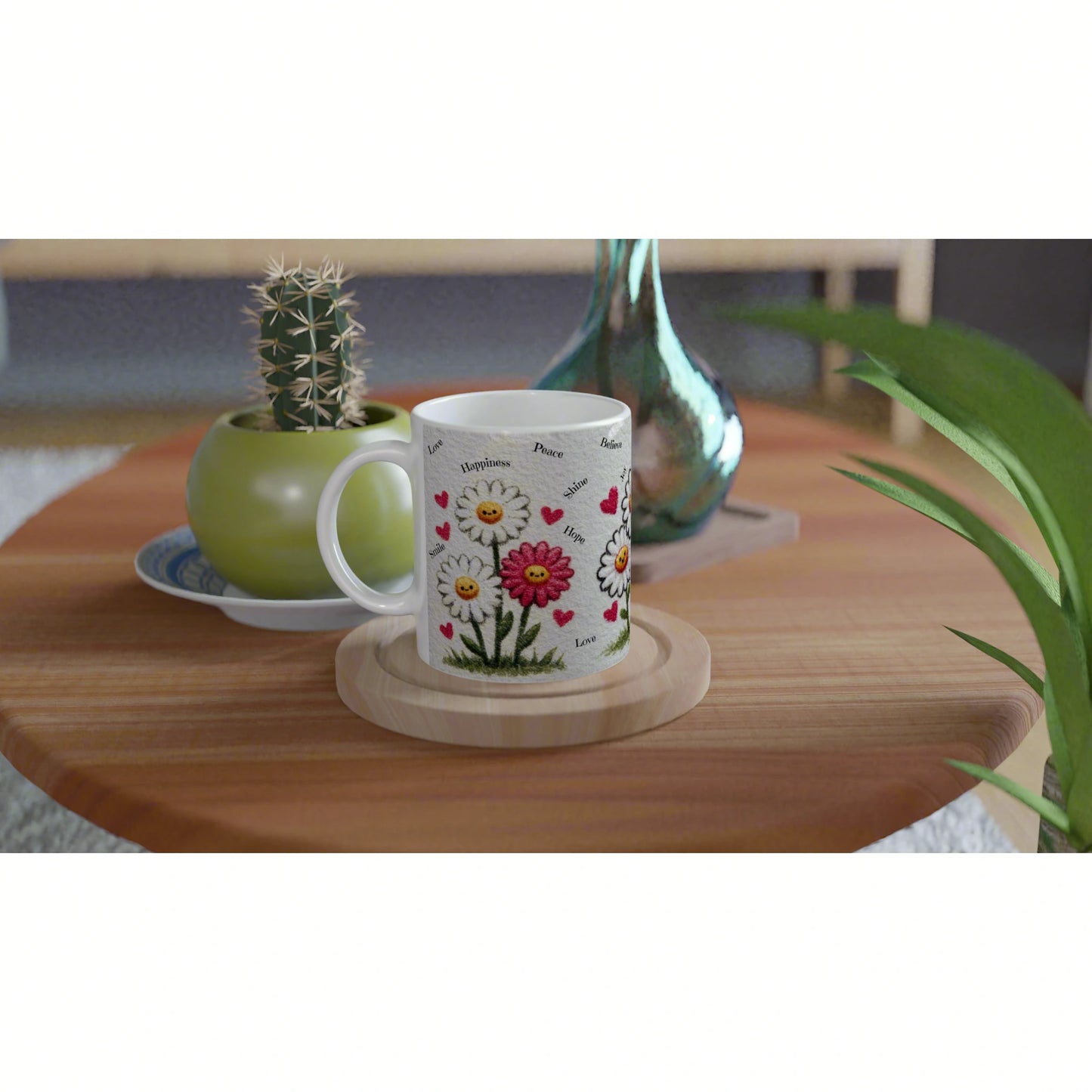 Product mockup: white mug with daisies, hearts and tiny words; sits on a wooden coaster beside a cactus and a vase.
