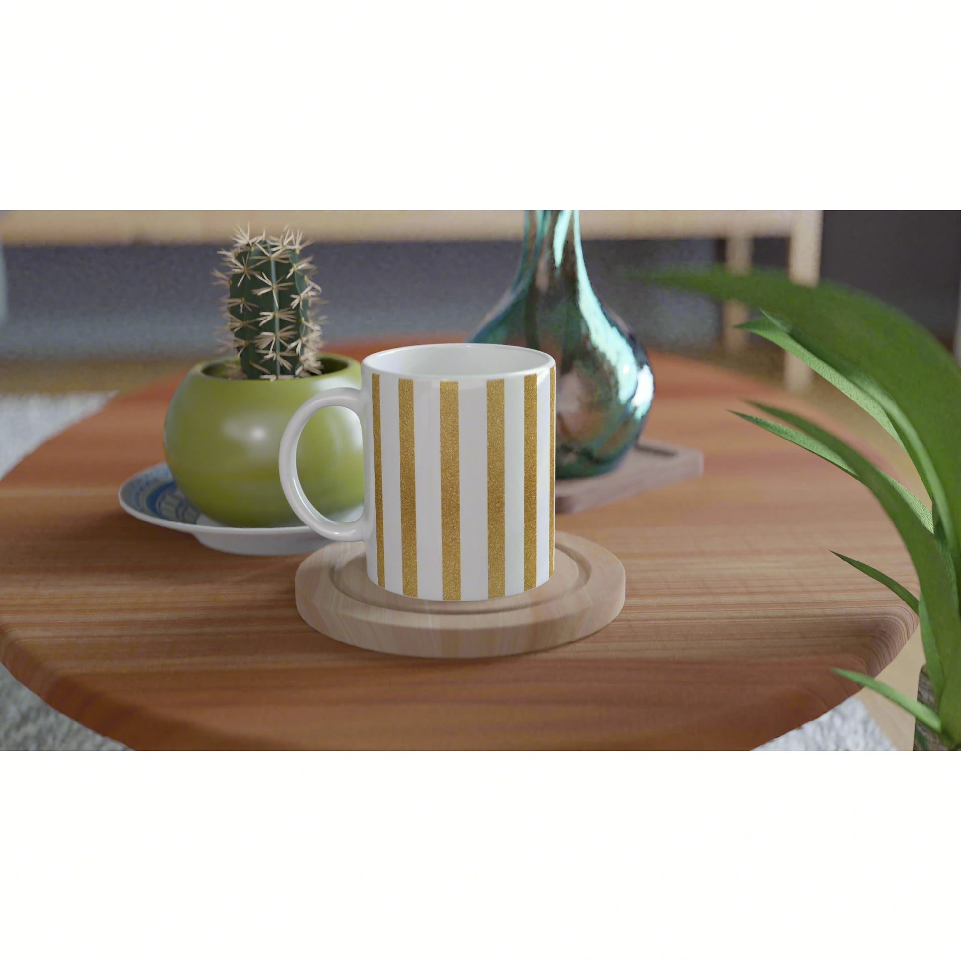 Product mockup: white mug with gold vertical stripes on a wooden coaster, on a table beside a cactus and teal vase.