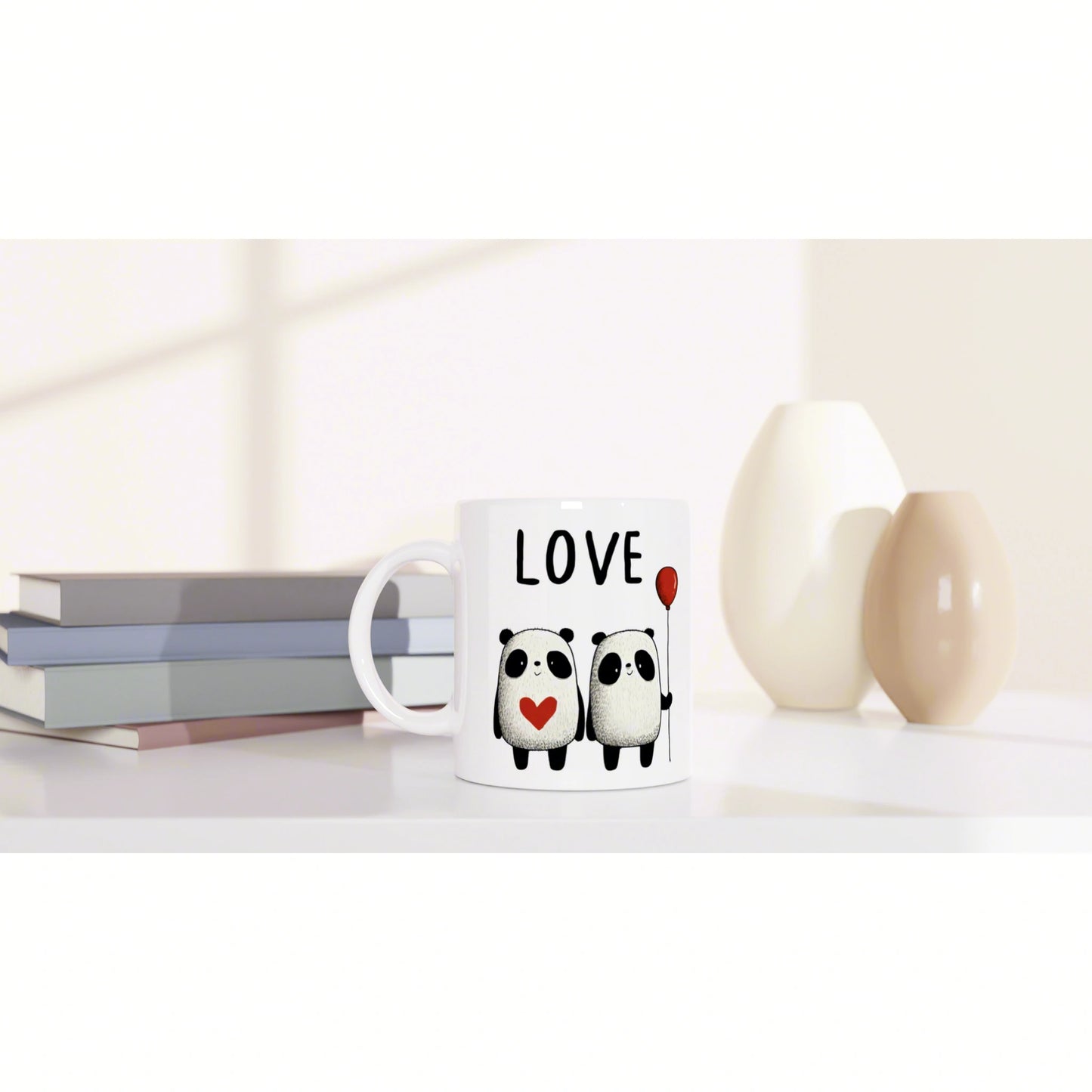 Product mockup: white mug with LOVE, two pandas, heart and balloon; background shows books and vases.