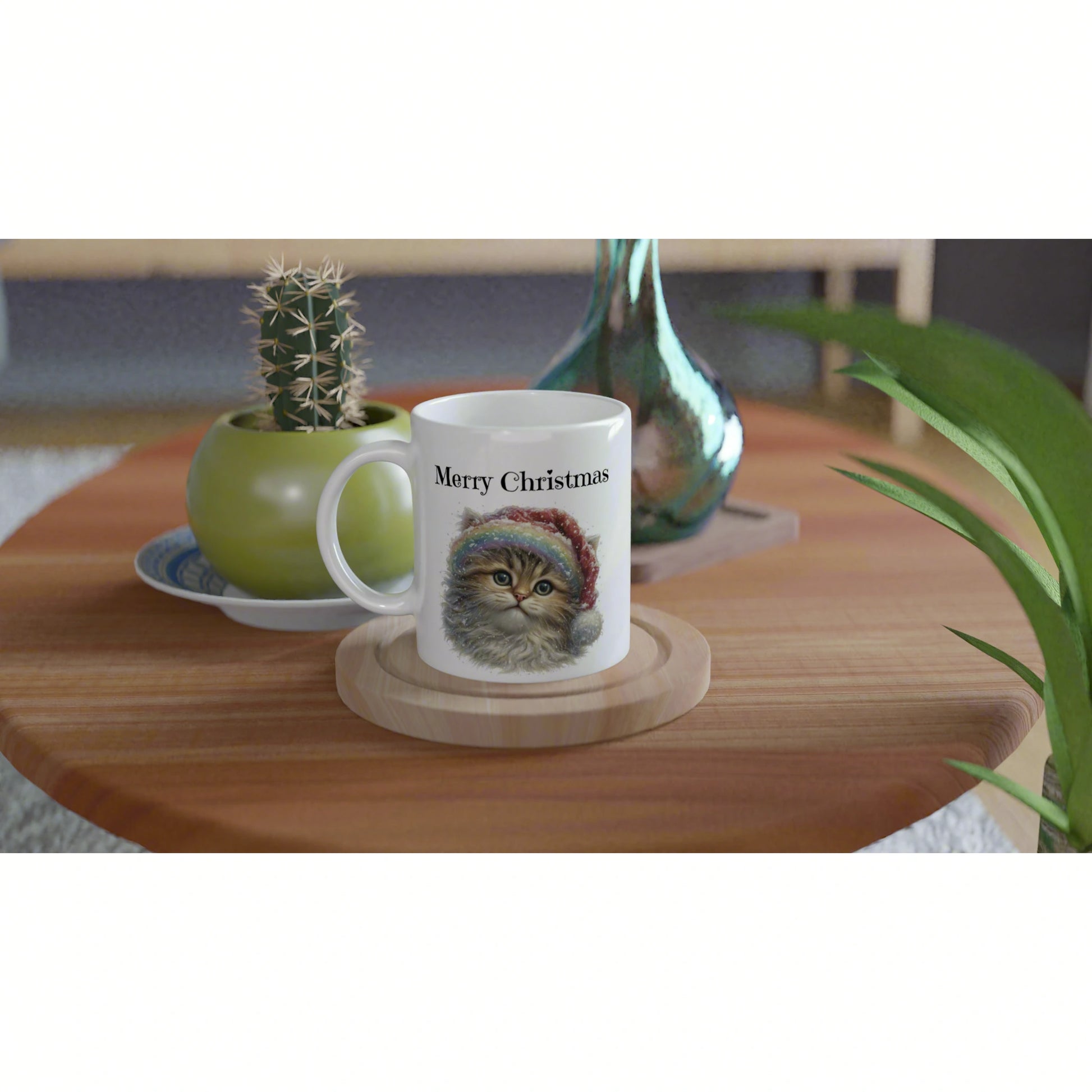 Product mockup: white mug with Merry Christmas and a fluffy cat in a Santa hat, on a wooden coaster beside plants.