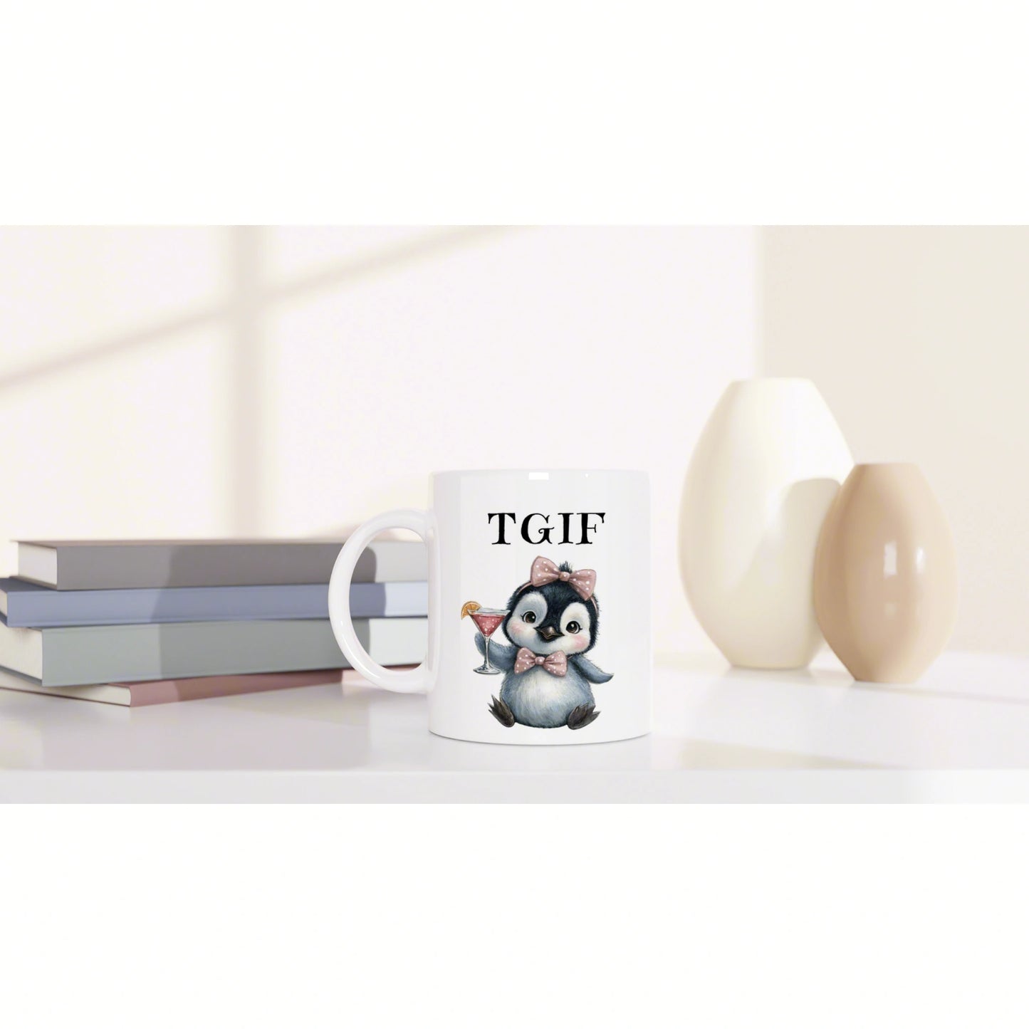 Product mockup: white mug with a penguin wearing a pink bow tie, holding a cocktail and 'TGIF' text, beside books and vases.