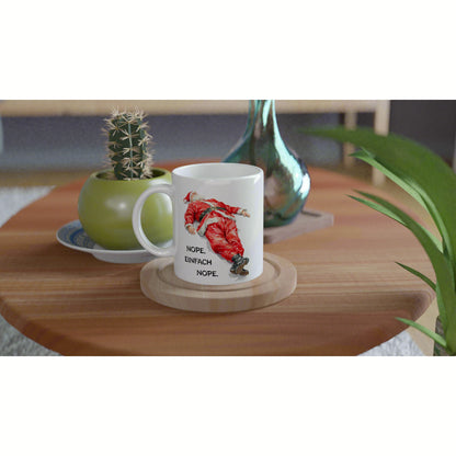 Product mockup: white mug on a wooden table featuring a red Santa illustration and the German text NOPE. EINFACH NOPE.