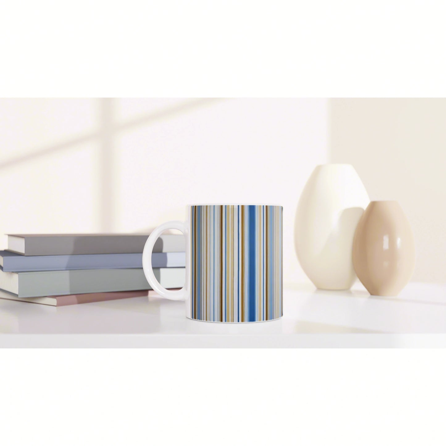 White mug with blue and beige vertical stripes on a shelf, beside a stack of books and two ceramic vases.