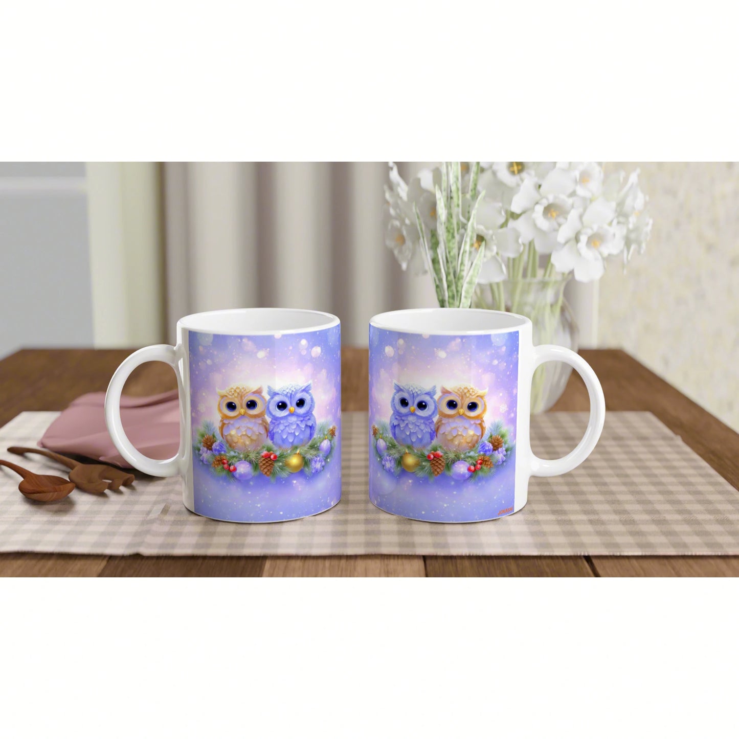 Two white mugs feature a cute owl illustration on a purple background; owls perched on a berry garland on a checkered placemat.