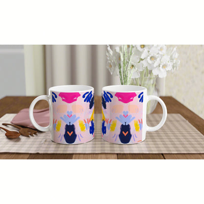 Two white ceramic mugs with a bright, abstract mirrored design on a wooden table, product mockup.